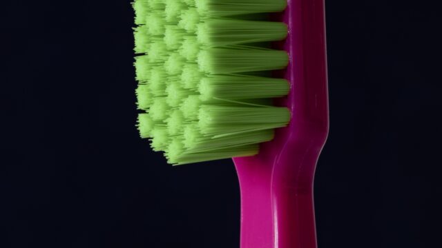 closeup photo of purple and green toothbrush